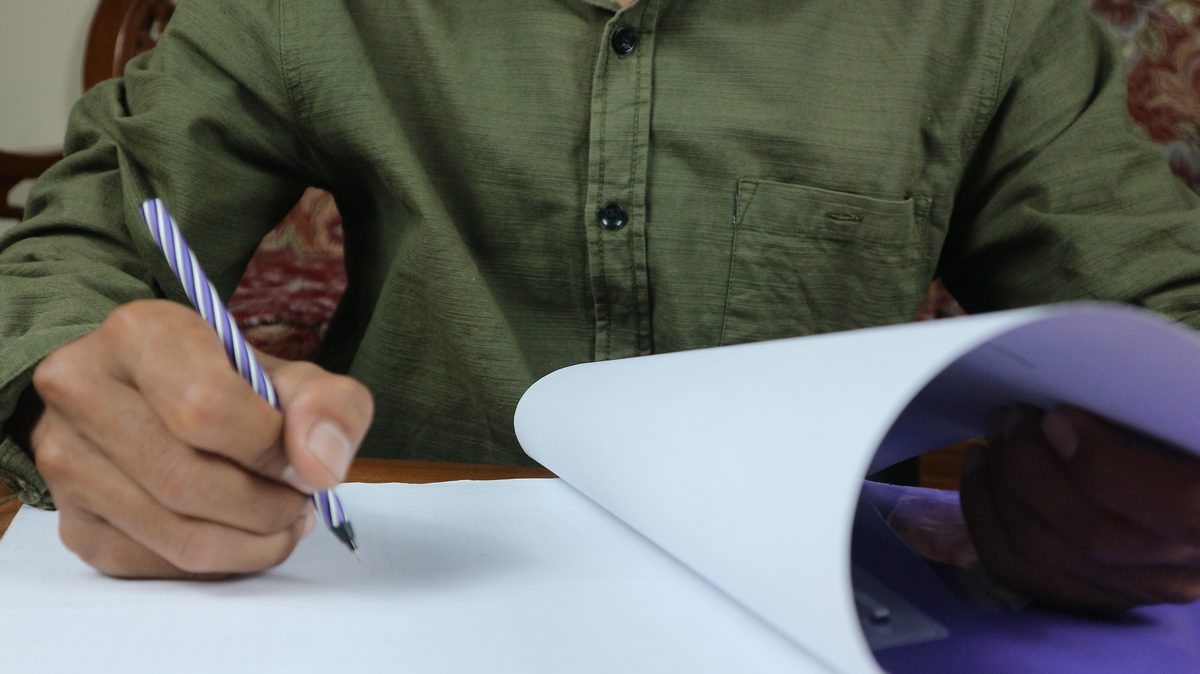 Close-up of a hand reviewing a printed page with a pen